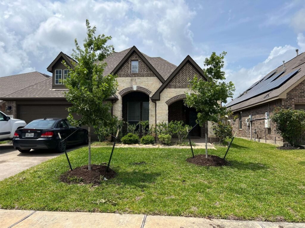 Two-story brick home with attached garage, landscaping, and solar panels on neighboring house.