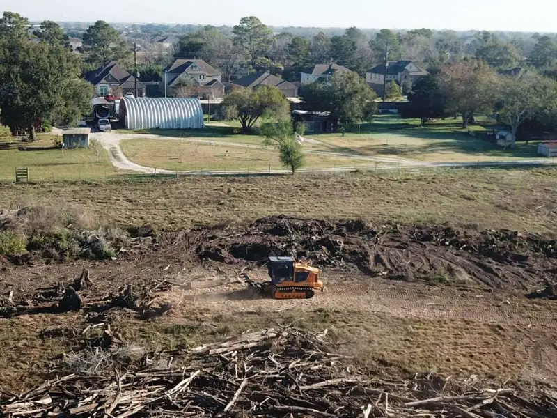 Orange tracked machine clearing land after storm damage. Tree services in Richmond, Texas.